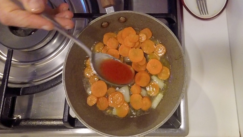 adding tomato puree to the carrot sauce