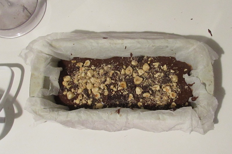 garnish the gluten-free chocolate loaf cake with hazelnuts and chocolate chips
