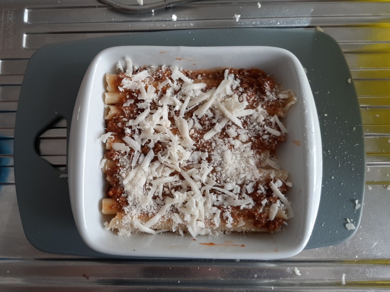 season first layer of baked ziti bolognese with sauce and grated cheese